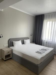 - une chambre avec un grand lit et une fenêtre dans l'établissement BnB Hotel Shymkent, à Chimkent