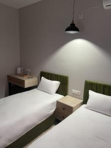 2 camas en una habitación con sábanas blancas y una lámpara en BnB Hotel Shymkent en Shymkent