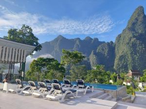 a group of chairs and a pool with mountains in the background at Magical Mountain View Resort in Khao Sok National Park