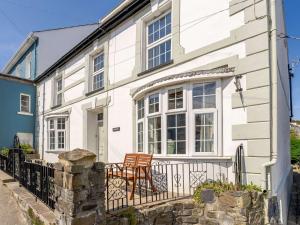 a white house with a chair on a balcony at 4 Bed in New Quay 78589 in New Quay