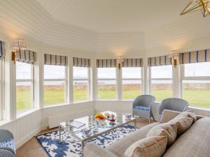 uma sala de estar com um sofá, uma mesa e janelas em 3 Bed in John O Groats CA337 em Mey