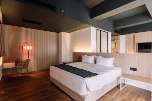 a bedroom with a bed and a table and a chair at Impiana by Roxy Hotel in Kuching