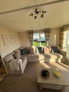 a living room with couches and a table at Bayview Bliss - Luxury Holiday Caravan - Northumberland in Newbiggin-by-the-Sea