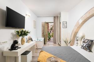 Elia Portou Luxury Residence في مدينة خانيا: غرفة نوم مع سرير وتلفزيون على الحائط