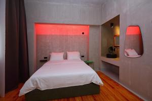 a bedroom with a white bed with a red light at Paradox in Thessaloniki