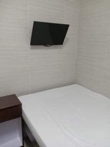 Habitación con cama y TV en la pared. en 富都賓館 Fu Dou Guest House en Hong Kong