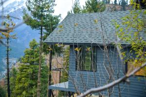 a blue house with a mountain in the background at Montane Chalet , Sethan in Manāli