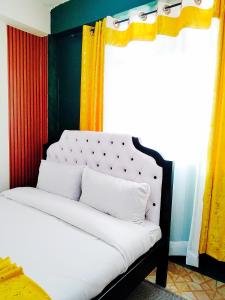 a bedroom with a white bed with yellow curtains at Cozy Haven Slumber in Nanyuki