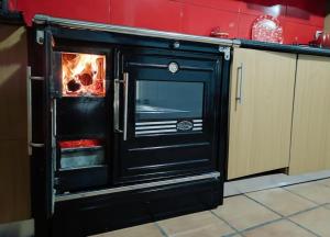einen schwarzen Ofen mit einem Feuer in der Küche in der Unterkunft Casa da Telhada Pequena in Melgaço