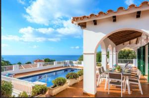 Un patio con mesa y sillas junto a una piscina. en Villa Úrsula, en Santo Tomás