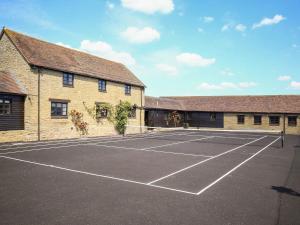 a tennis court in front of a building at Finest Retreats - The Park in Onibury