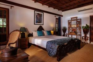 BluSalzz Escapade - Muhamma, Alleppey - Kerala في أليبي: غرفة نوم بسرير وكرسي في غرفة