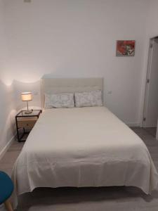 ein großes weißes Bett in einem Schlafzimmer mit einer Lampe in der Unterkunft Cozy studio for 2 people in Gran Via.SI2A2 in Madrid
