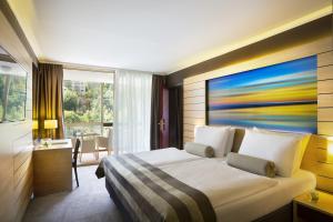 a hotel room with a bed with a painting on the wall at Hotel Excelsior - Liburnia in Lovran
