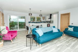 a living room with a blue couch and pink chairs at High Tide Lodge in Gatehouse of Fleet