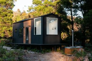 una pequeña casa negra pequeña con una ventana grande en Wild Life Cabin 2 - Grampians, en Halls Gap