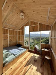 a bedroom with a bed and a desk and windows at Midori Coffee Farm in Da Lat