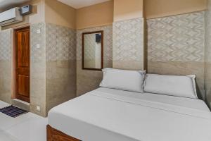 a bedroom with a large bed with white pillows at OYO Flagship Sree Vishnu Bhavan in Tirupati