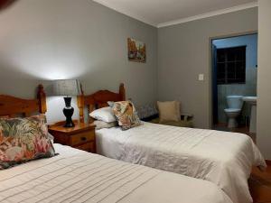 a bedroom with two beds and a lamp and a chair at Magalies House in Pretoria