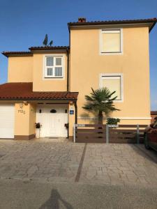 a house with a garage and a palm tree in front of it at Apartment Liznjan 3 in Ližnjan