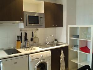 uma cozinha com uma máquina de lavar roupa e um micro-ondas em Apartamento Calle Mauricio Legendre em Madri