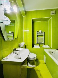 Baño amarillo con lavabo y aseo en Hotel Flora en Drobeta-Turnu Severin