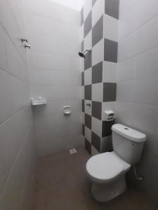 a bathroom with a white toilet and a checkered wall at D'homestay Parit Buntar in Parit Buntar