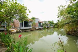 a river in a village with houses and trees at Busaya Resort & Cuisine in Nakhon Pathom