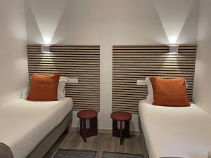 プライア・デ・ミラにあるGranny´s Guesthouseのオレンジ枕付きのベッド2台が備わる客室です。