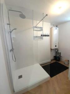 La salle de bains est pourvue d'une douche et d'un mur blanc. dans l'établissement Meublé cosy T3 centre ville (2), à Châteauroux