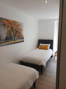 two beds in a room with a painting on the wall at Gîte Manoir de Kerlez Plain-pied in Briec