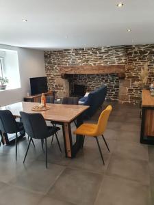 een eetkamer met een tafel en stoelen en een open haard bij Gîte Manoir de Kerlez in Briec