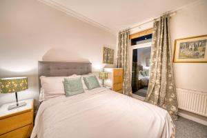 Schlafzimmer mit einem weißen Bett und einem Fenster in der Unterkunft Luxury Terraced Victorian House in London