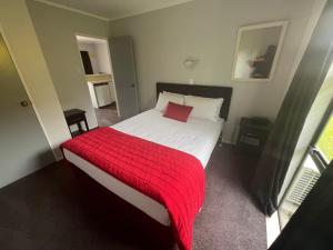 a bedroom with a bed with a red blanket at Avenue Motel Palmerston North in Palmerston North