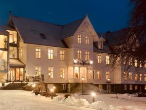 un gran edificio blanco por la noche en la nieve en Gloppen Hotell - by Classic Norway Hotels, en Sandane