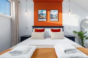 a bedroom with a large bed with an orange wall at The Stylish 3-Bedroom Maisonette Retreat in Stirling