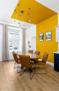 uma mesa de jantar com cadeiras e uma parede amarela em The Stylish 3-Bedroom Maisonette Retreat em Stirling
