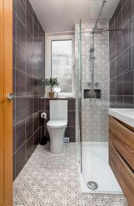 a bathroom with a toilet and a glass shower at The Stylish 3-Bedroom Maisonette Retreat in Stirling