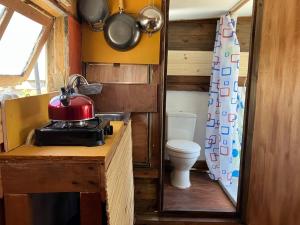 uma pequena cozinha com WC e uma panela vermelha no balcão em Solar Valizas em Barra de Valizas