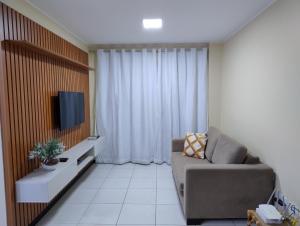 a living room with a couch and a tv at Prainha Aconchegante apto de quarto e sala com vista para o mar in Arraial do Cabo