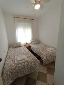 2 camas en una habitación pequeña con ventana en Apartamento Urba Ruta del Veleta, en Cenes de la Vega