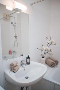 een witte badkamer met een wastafel en een spiegel bij Stylish Apartment with breathtaking rooftop views in Wenen