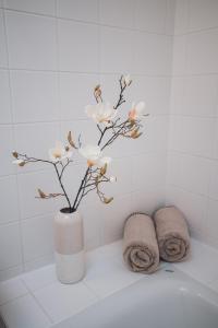 een witte vaas met witte bloemen in de badkamer bij Stylish Apartment with breathtaking rooftop views in Wenen