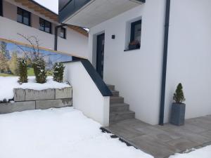 a white house with snow on the stairs at Ferienwohnung Riedmann in Söll