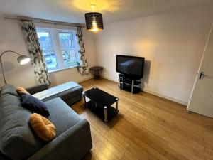 een woonkamer met een bank en een flatscreen-tv bij Spacious 2BR Flat with Sofa-Bed in Central Reading in Reading