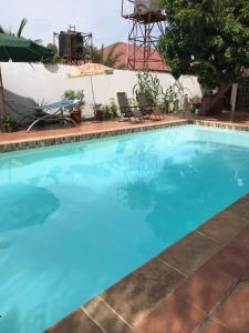 a large blue swimming pool with two chairs at B & B Villa Calliandra in Bijilo