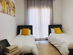 two beds with yellow pillows in a room with a window at Harav Kuk Royal Suites - Alefimmoed in Jerusalem