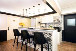 a kitchen with a bar with black chairs at Pillows CoLiving in Hong Kong