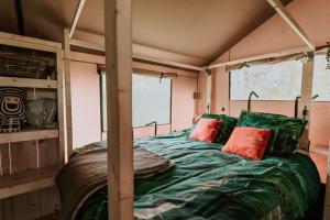 a bedroom with a bed with green sheets and red pillows at Kampari in Delfstrahuizen