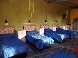 four beds in a room with blue sheets at Sentir Indiano in Valeria del Mar